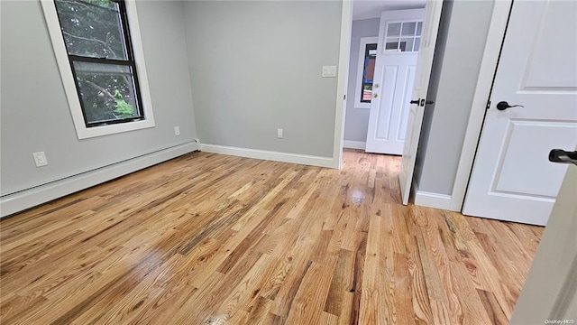 spare room with a baseboard heating unit and light hardwood / wood-style floors