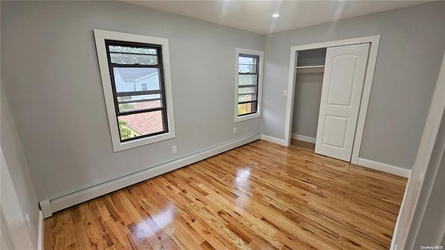 unfurnished bedroom with a baseboard radiator, light wood-type flooring, and a closet