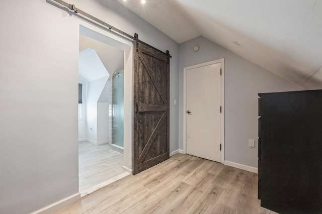 additional living space featuring lofted ceiling, a barn door, and light hardwood / wood-style flooring