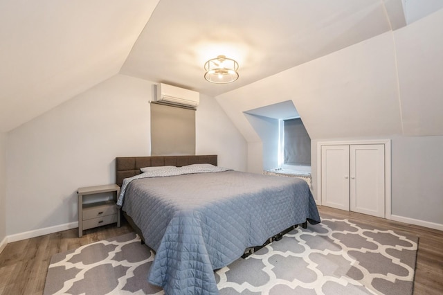 bedroom with wood-type flooring, vaulted ceiling, and a wall unit AC