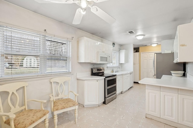 kitchen with white cabinetry, sink, stainless steel appliances, and ceiling fan