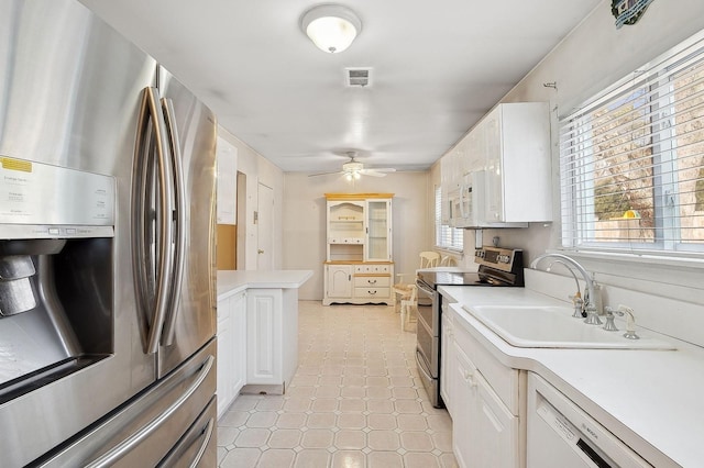 kitchen featuring appliances with stainless steel finishes, sink, white cabinets, and ceiling fan