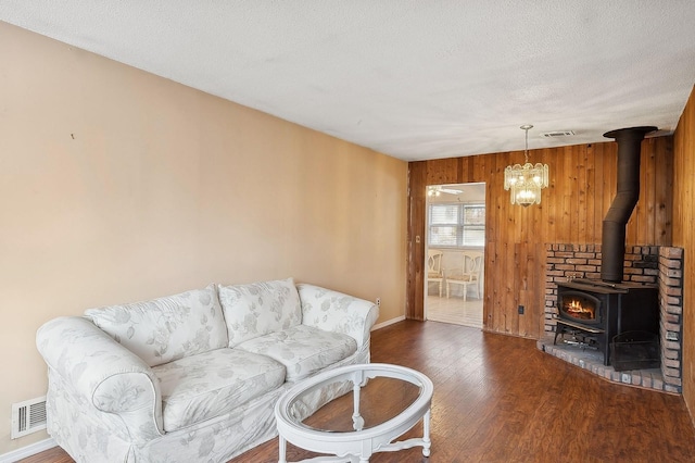 living room featuring dark wood-type flooring, a wood stove, a textured ceiling, and wood walls