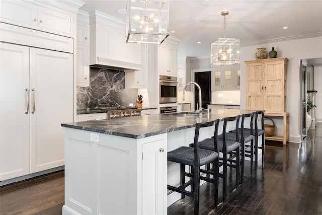 kitchen featuring white cabinetry, a large island, decorative light fixtures, and sink