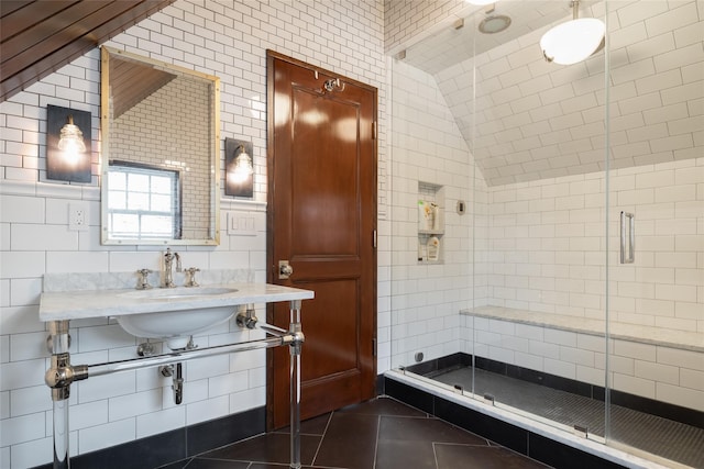 bathroom featuring tile patterned flooring, lofted ceiling, tile walls, and walk in shower