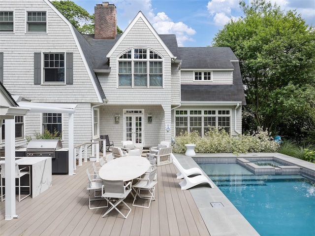 back of house with french doors, area for grilling, and a pool with hot tub