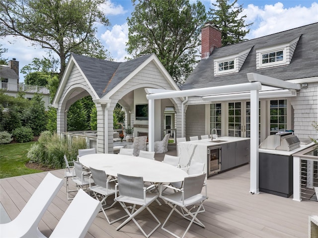 wooden deck featuring exterior kitchen, sink, beverage cooler, and a fireplace