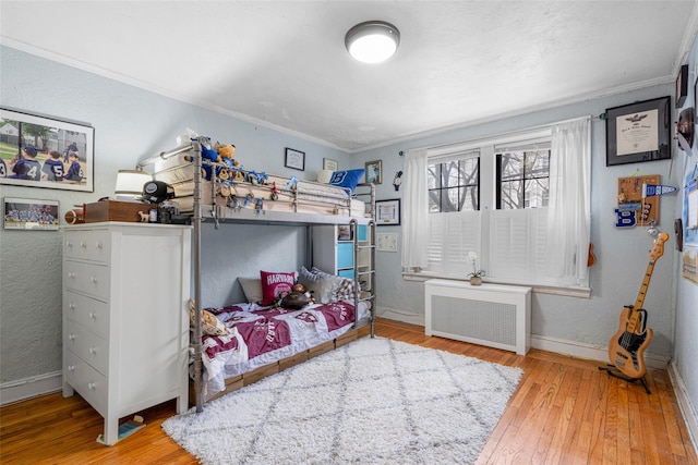 bedroom featuring radiator, ornamental molding, and hardwood / wood-style flooring