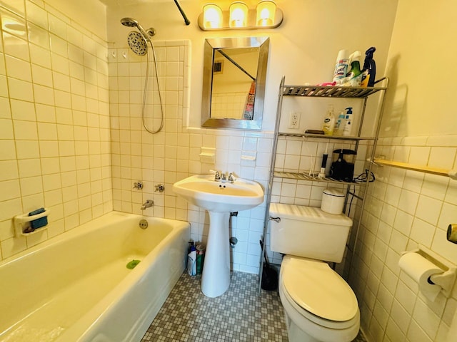 bathroom with tile patterned floors, toilet, tiled shower / bath combo, and tile walls