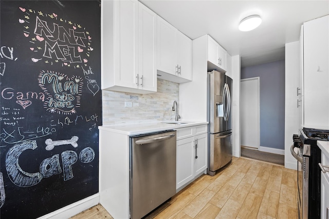 kitchen with white cabinetry, appliances with stainless steel finishes, light hardwood / wood-style floors, and sink