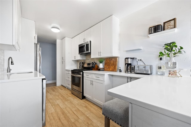 kitchen featuring tasteful backsplash, sink, white cabinets, a kitchen breakfast bar, and stainless steel appliances