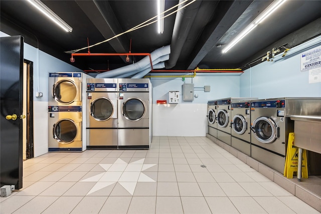 laundry room featuring tile patterned flooring, stacked washer / dryer, electric panel, and washing machine and dryer