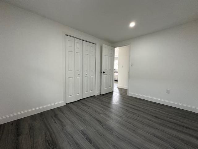 unfurnished bedroom with dark hardwood / wood-style floors and a closet