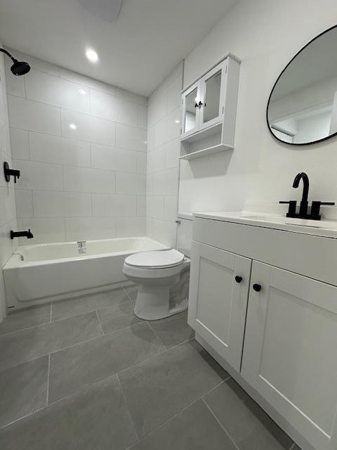 full bathroom featuring tiled shower / bath, vanity, and toilet