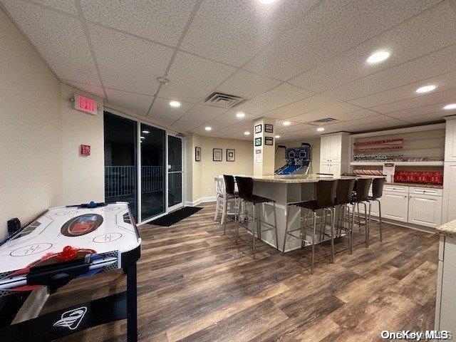 bar with white cabinetry, light stone counters, a paneled ceiling, and dark hardwood / wood-style floors