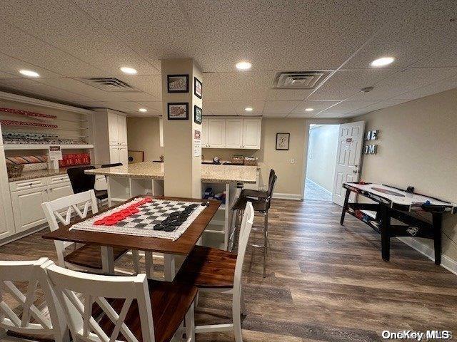 dining space with dark hardwood / wood-style floors and a drop ceiling