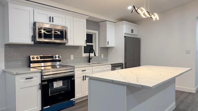 kitchen with a kitchen island, white cabinetry, sink, light stone counters, and stainless steel appliances