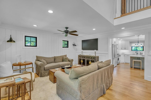 living room with sink, ornamental molding, light hardwood / wood-style floors, and ceiling fan