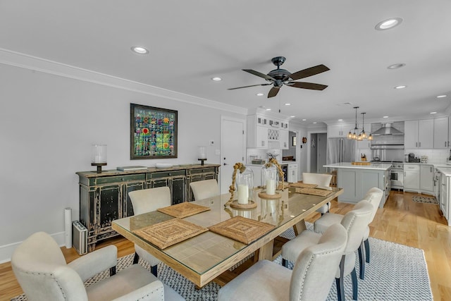 dining room with ceiling fan with notable chandelier, light hardwood / wood-style flooring, and ornamental molding