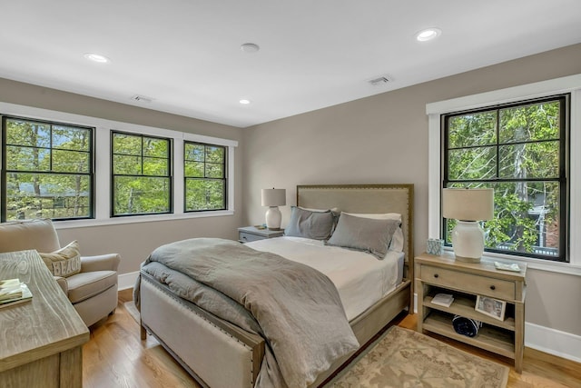 bedroom with multiple windows and light hardwood / wood-style floors