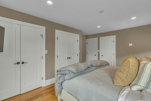 bedroom with two closets and light wood-type flooring