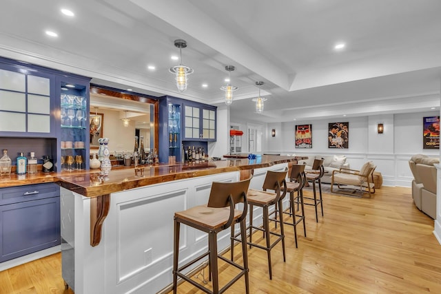 bar featuring pendant lighting, butcher block countertops, light hardwood / wood-style floors, and blue cabinets