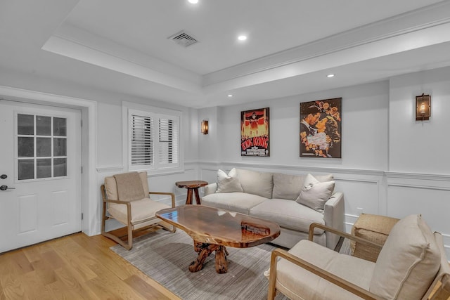 living room featuring a tray ceiling and light hardwood / wood-style floors