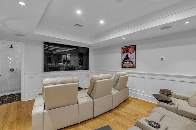 home theater featuring a raised ceiling and light wood-type flooring