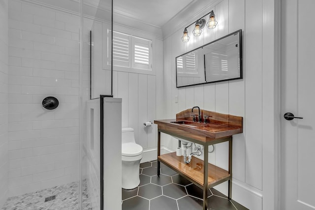 bathroom with tiled shower, toilet, tile patterned flooring, and sink