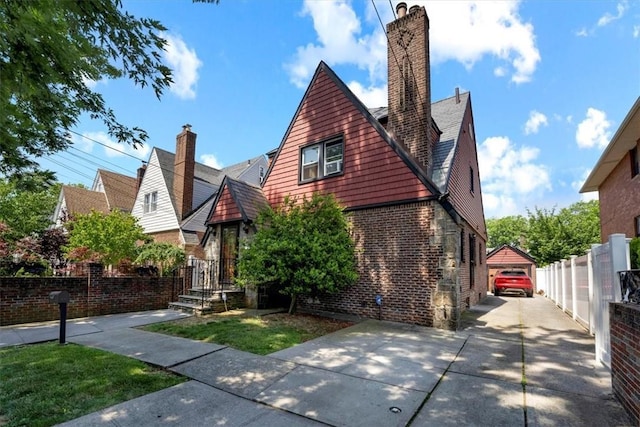 tudor-style house featuring a garage and an outbuilding