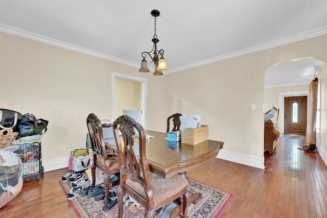 dining area with a notable chandelier, crown molding, and wood-type flooring