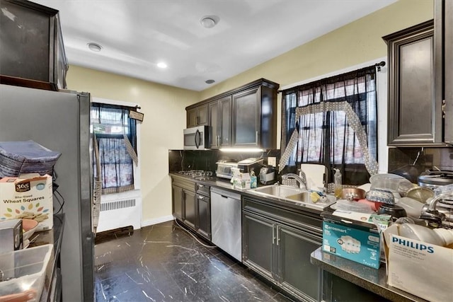 kitchen with tasteful backsplash, sink, dark brown cabinets, and appliances with stainless steel finishes