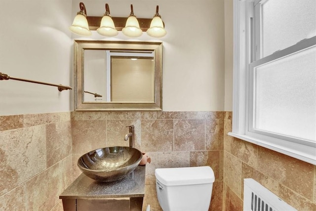 bathroom with radiator heating unit, toilet, tile walls, and vanity