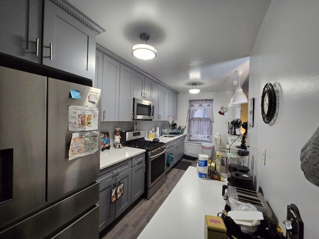 kitchen with dark wood-type flooring, stainless steel appliances, gray cabinets, and tasteful backsplash