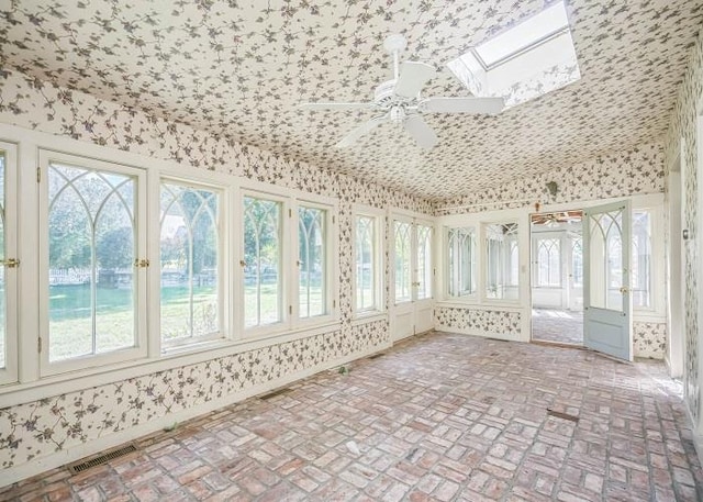 unfurnished sunroom with ceiling fan and a skylight