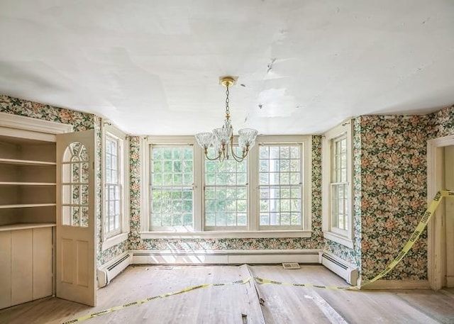 unfurnished dining area with baseboard heating, a notable chandelier, light wood-type flooring, and a wealth of natural light