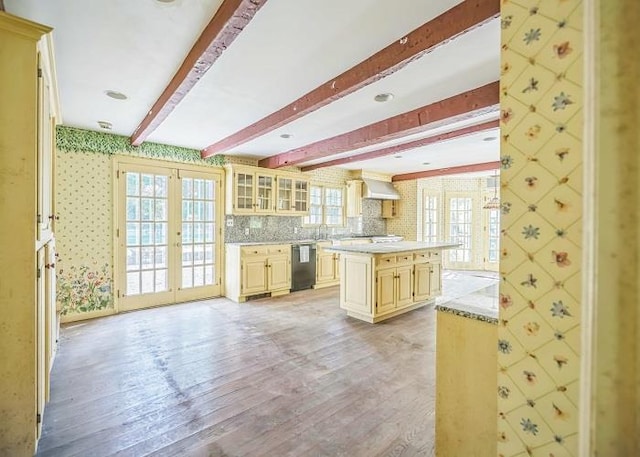 kitchen with a kitchen island, dishwasher, light hardwood / wood-style floors, wall chimney range hood, and french doors