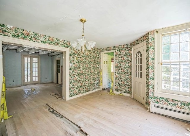 unfurnished dining area featuring french doors, a healthy amount of sunlight, wood-type flooring, and a baseboard heating unit