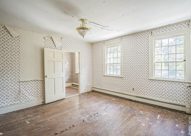 unfurnished bedroom with hardwood / wood-style flooring and baseboard heating