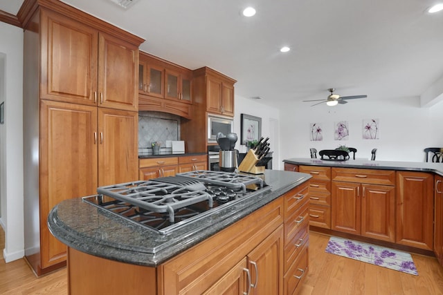 kitchen featuring a center island, brown cabinets, light wood-style flooring, and black gas stovetop