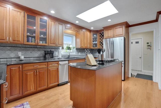 kitchen featuring brown cabinetry, a skylight, and light wood-style flooring