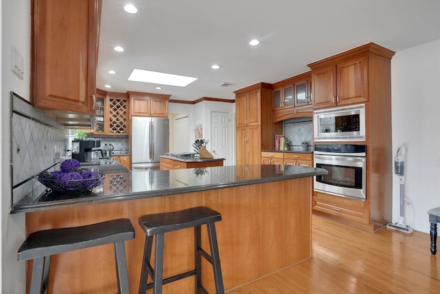 kitchen featuring dark countertops, stainless steel appliances, a peninsula, and backsplash