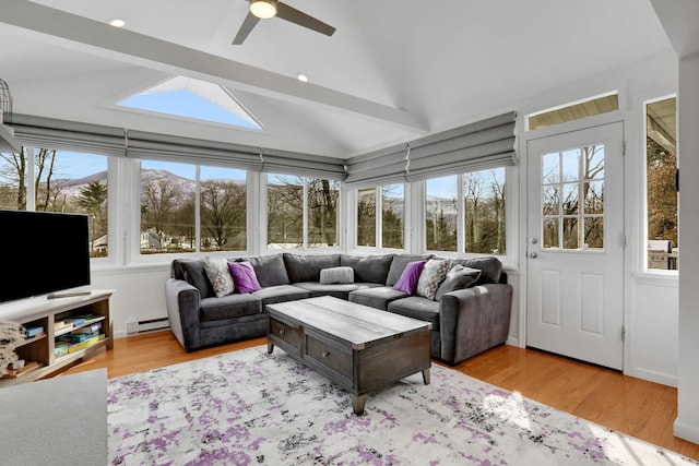 sunroom / solarium featuring a ceiling fan, vaulted ceiling, baseboard heating, and a mountain view