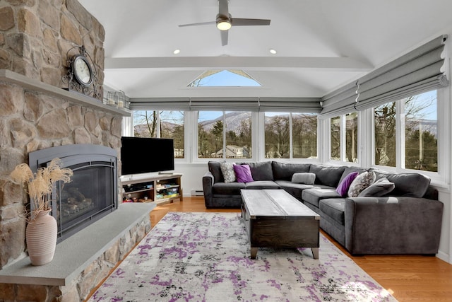 living area with lofted ceiling, a fireplace, wood finished floors, and a wealth of natural light