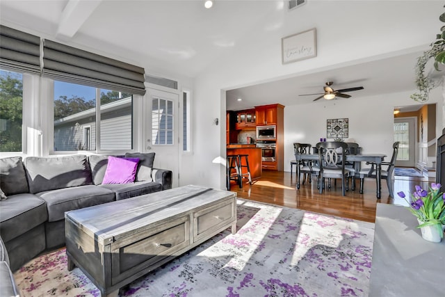 living area with lofted ceiling, recessed lighting, wood finished floors, visible vents, and a ceiling fan