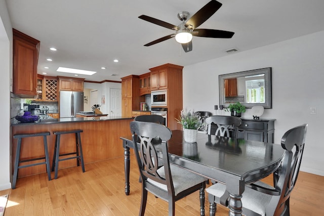 dining area with light wood-style flooring, recessed lighting, a skylight, visible vents, and a ceiling fan