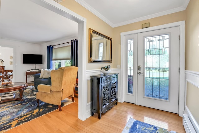 entryway with crown molding, a baseboard radiator, plenty of natural light, and light wood finished floors