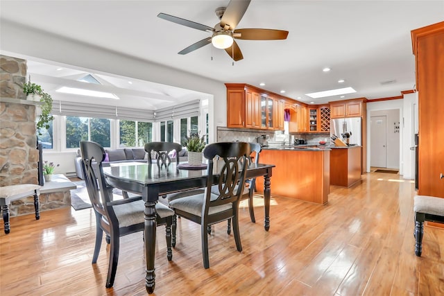 dining area with light wood finished floors, a skylight, a ceiling fan, and recessed lighting