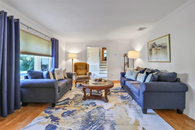 living room with stairway, visible vents, wood finished floors, and ornamental molding