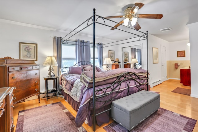 bedroom featuring visible vents, baseboards, wood finished floors, crown molding, and a baseboard heating unit